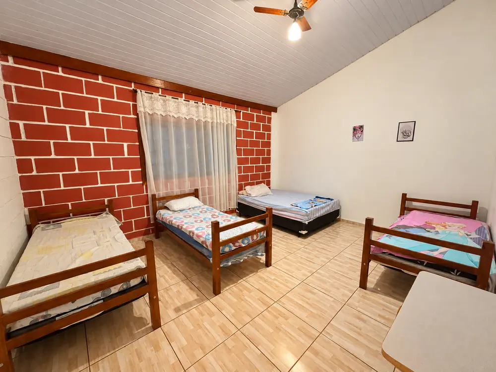 Quarto com quatro camas de solteiro e cortina rendada